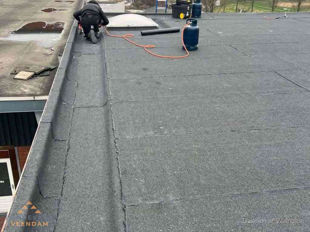 Dakdekker repareert bitumen dakbedekking op groot plat dak in Veendam