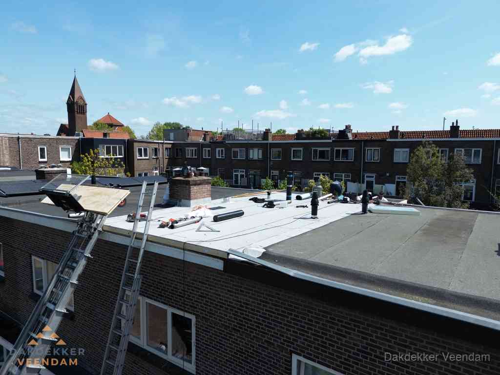 Dakdekkers aan het werk op plat dak in Veendam