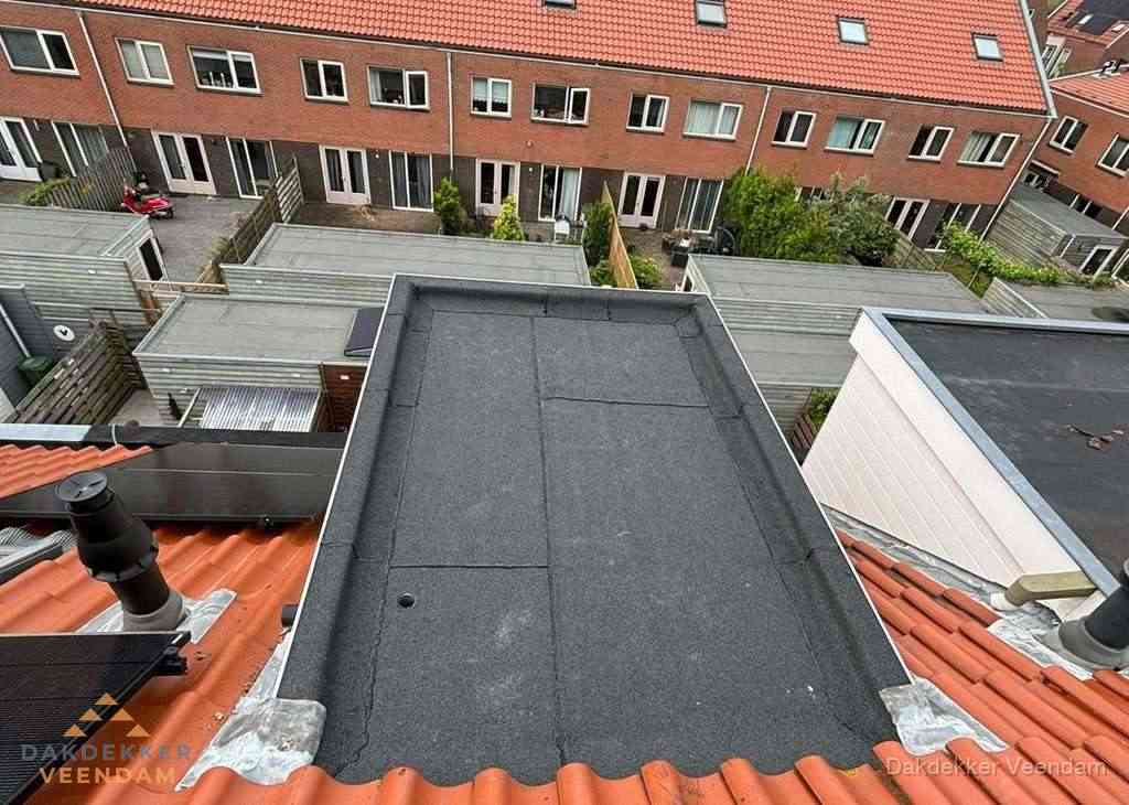 Plat dak met bitumen bedekking naast dakkapel in Veendam