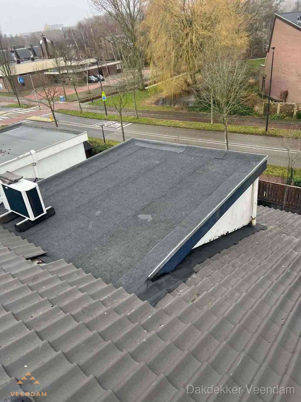 Plat dak met bitumen dakbedekking naast schuin pannendak in Veendam