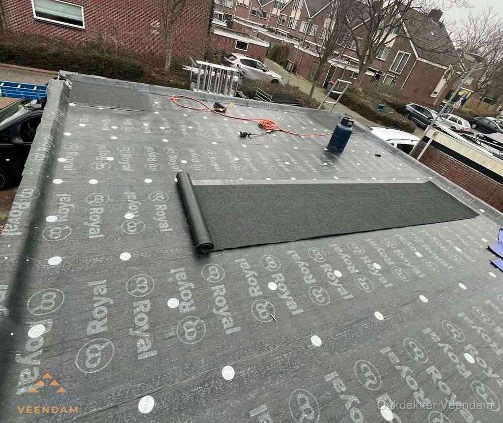 Dakdekker aan het werk met gasbrander op plat bitumen dak in Veendam
